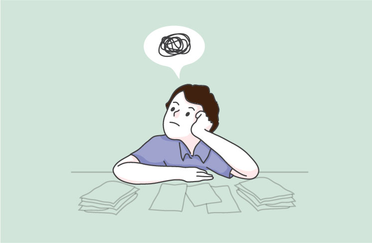 机に頬杖をついて悩む少年