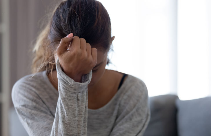 頭に手を当てて苦悩する女性