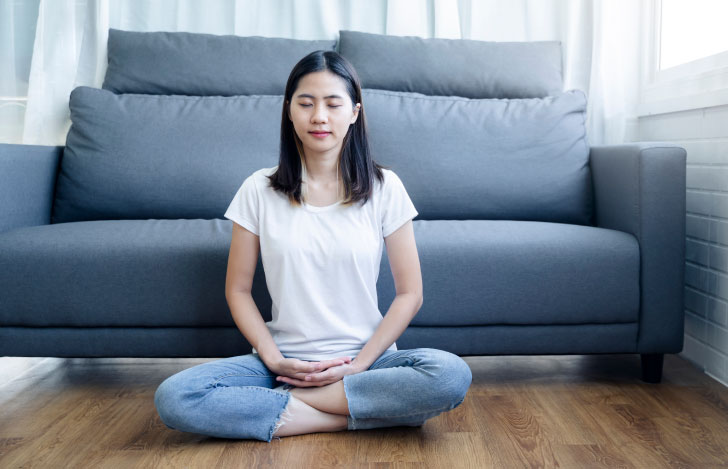 ソファの前で瞑想する女性