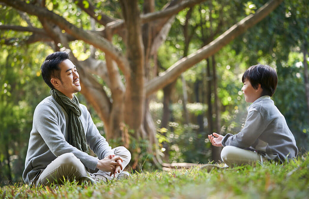 自然の中であぐらで座る親子