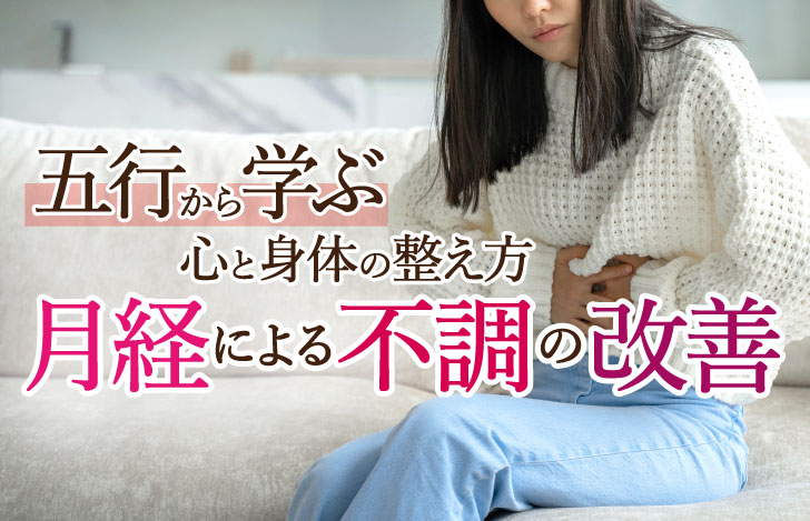 ソファに座って腹部を押さえる女性