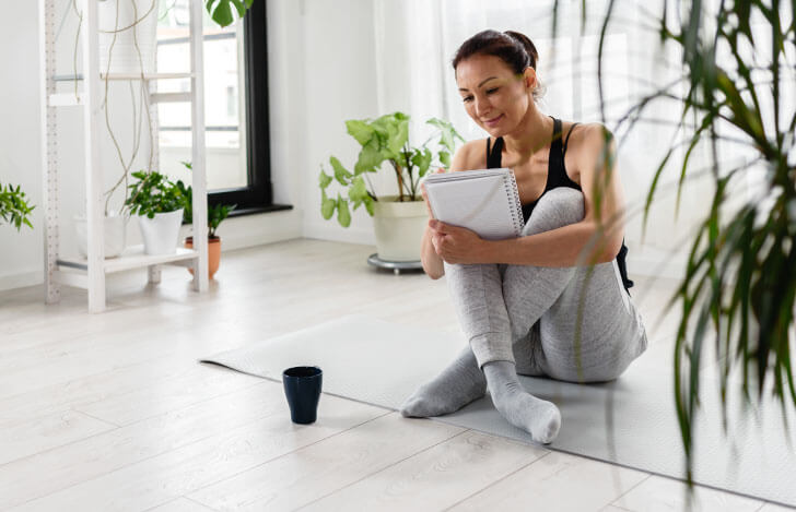 ヨガマットに座り勉学に励女性