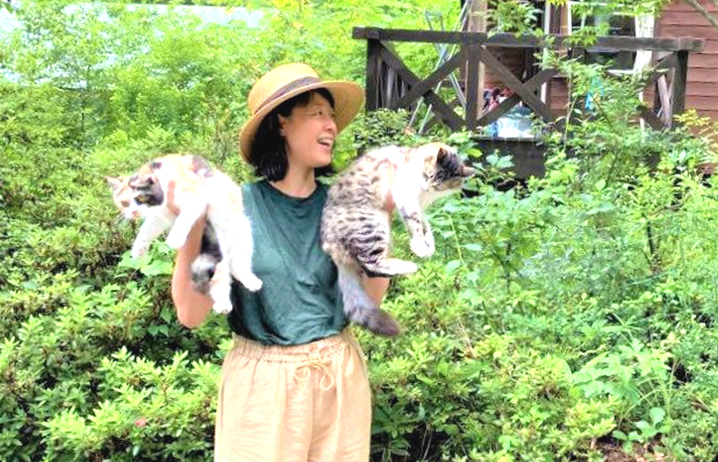 緑の前で両手に猫を抱えるいずみ先生
