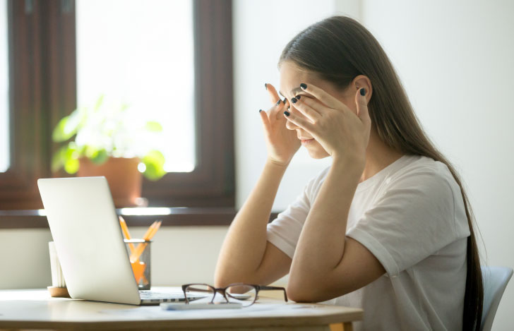 目の疲れのために目元を手で押さえる女性