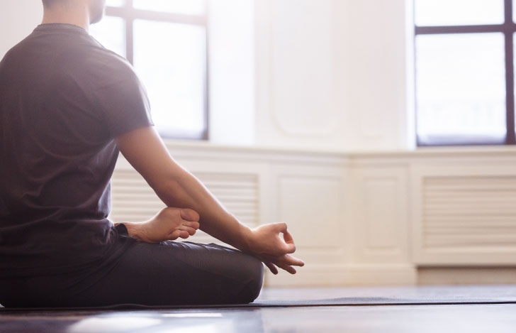 ヨガマットに座る男性の後ろ姿