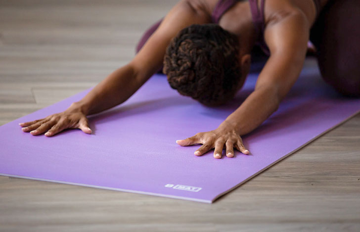 ヨガマットの上でチャイルドポーズをとる女性