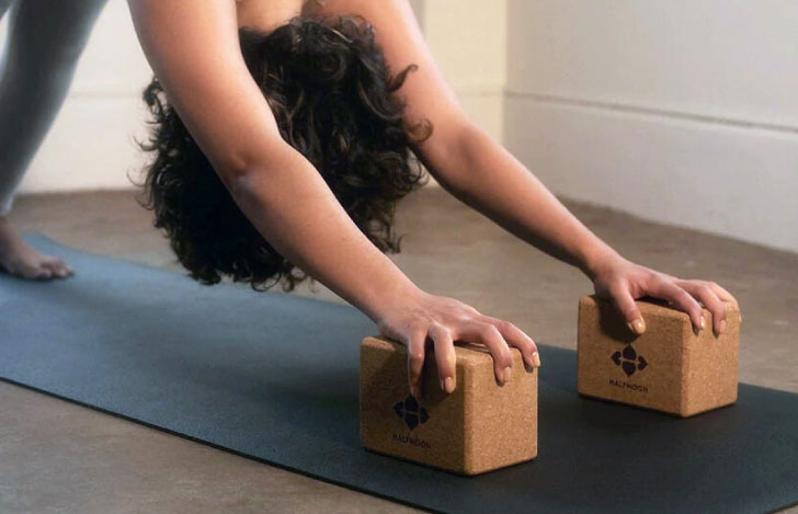 ヨガブロックを使ってヨガの練習を行う女性