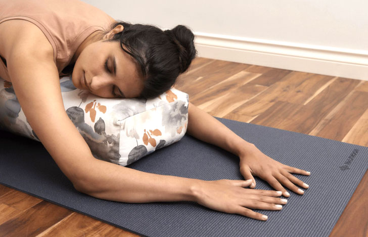 ボルスターを使ってヨガの練習を行う女性