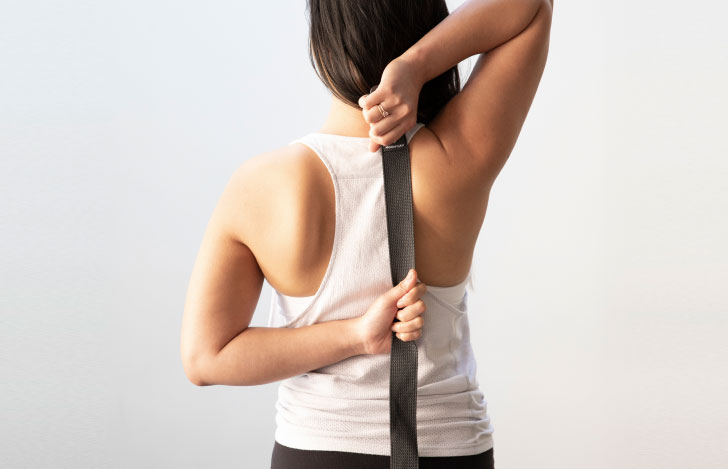 ヨガストラップを使ってヨガの練習を行う女性