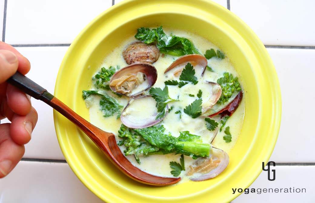 黄色の器に盛り付けた菜の花とアサリのスパイシーなミルクスープ
