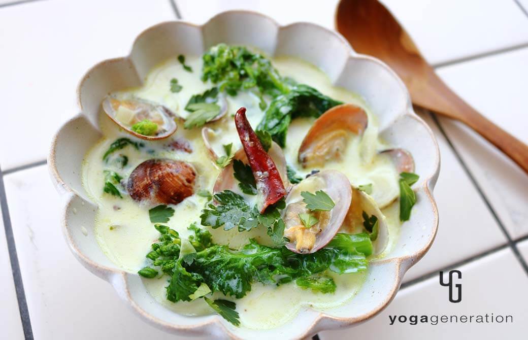 白い花形の器に盛り付けた菜の花とアサリのスパイシーなミルクスープ