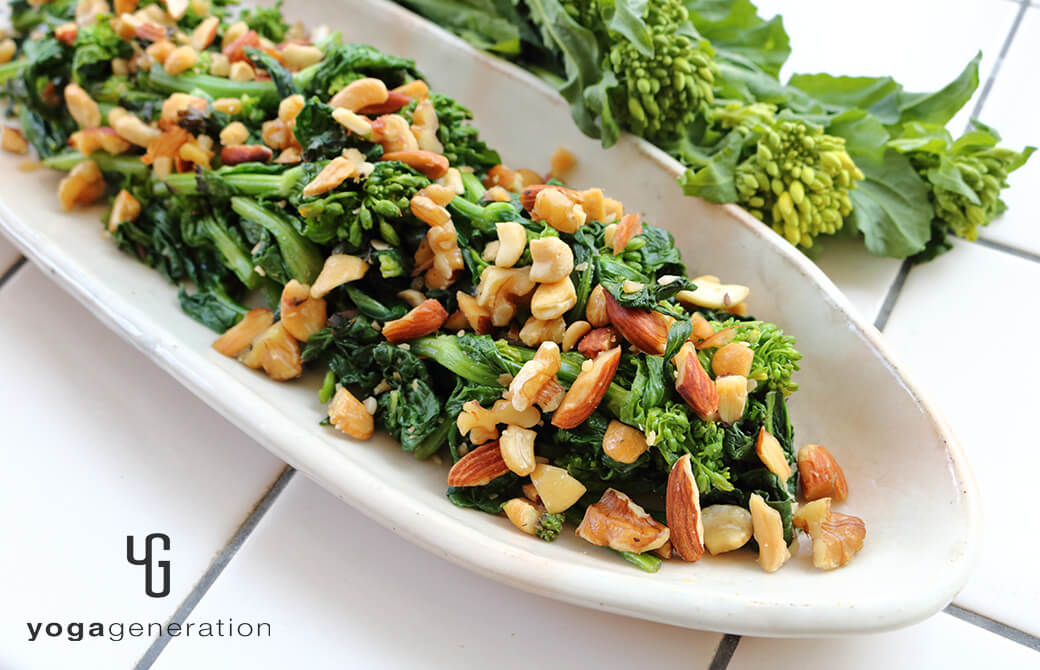 淡いピンクのお皿に盛り付けた菜の花と色々ナッツの塩炒め