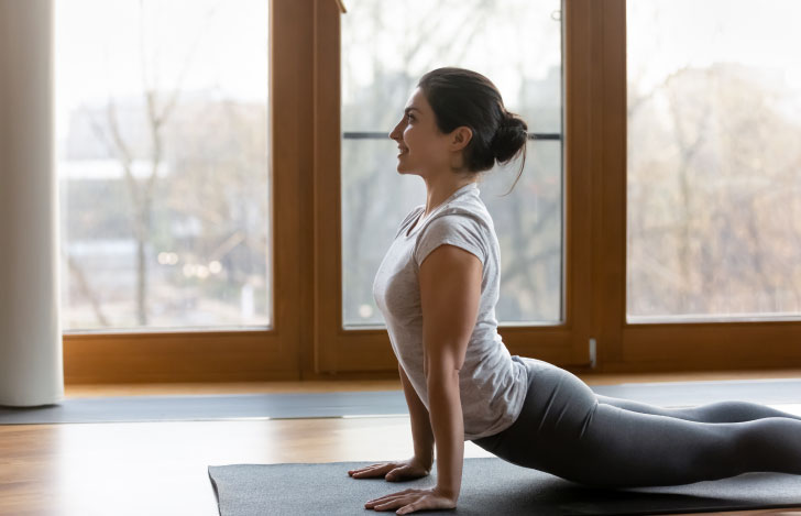 微笑みを浮かべながらヨガの練習を行う女性