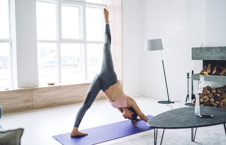 室内で片足のダウンドッグを行う女性