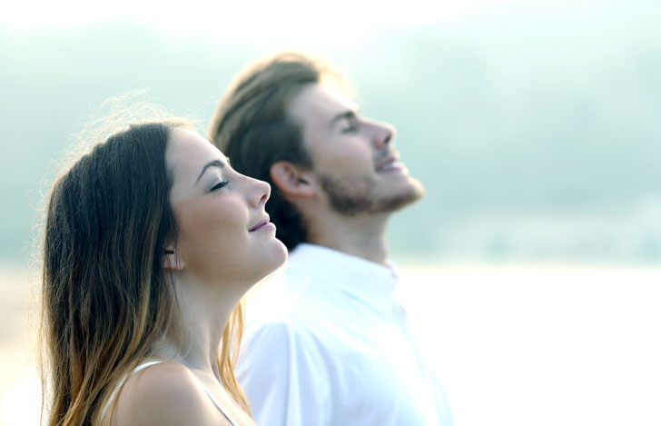 屋外で目を閉じて呼吸する男女