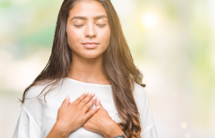 両手を胸に当てて目を閉じる女性