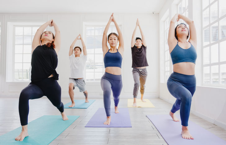 室内のヨガマットの上でハイランジを行う人々