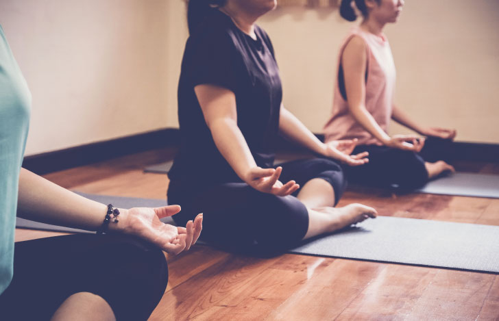 安楽座でヨガマットに座る3人の女性