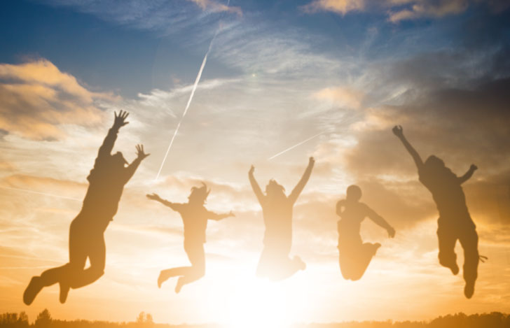 夕日を背景に元気よくジャンプする人々のシルエット