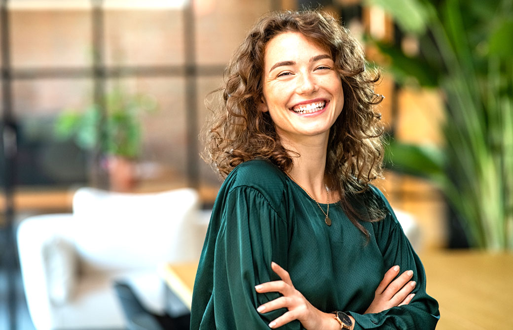 腕を組んで笑顔の緑色の服を着た女性