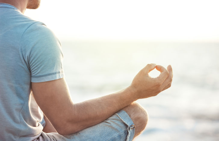 海に向かって安楽座で座る男性