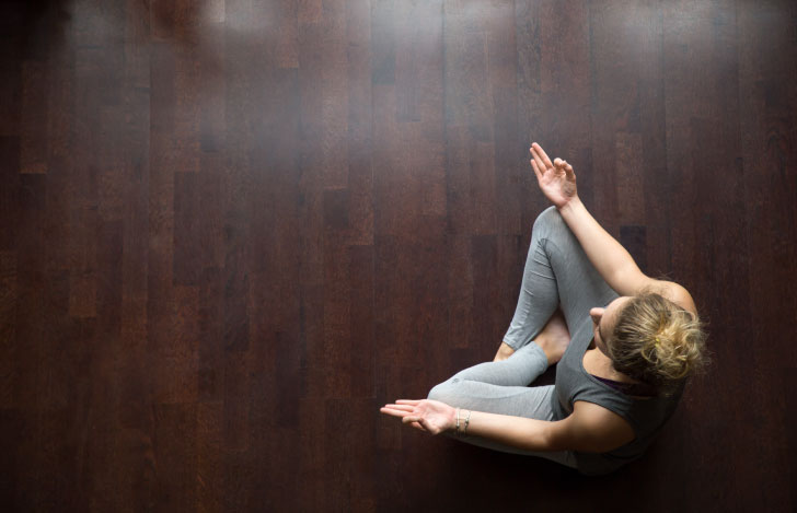 木の床に安楽座で座る女性を上から見たところ