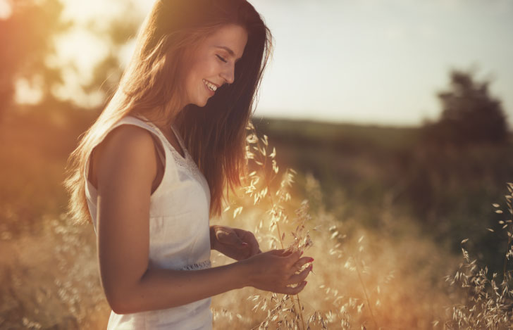 手に植物を持ち微笑みを浮かべる長い髪の女性