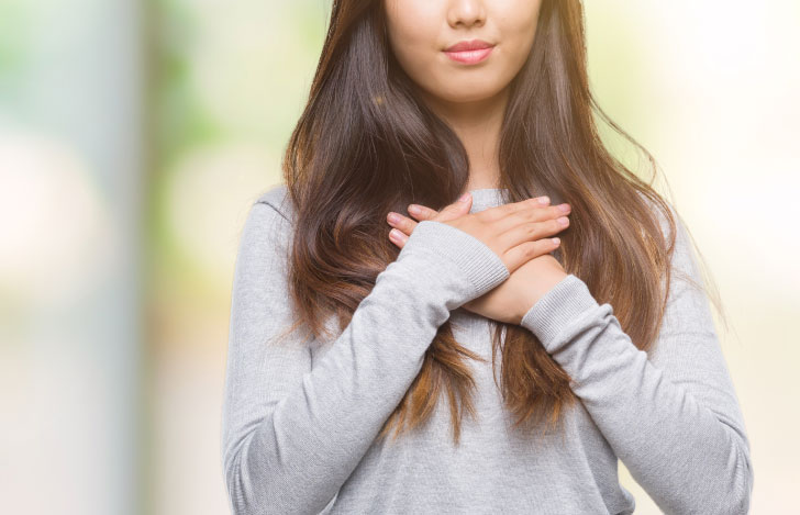 胸に手を当てて口元に微笑みを浮かべるる女性