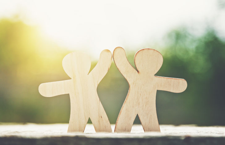 ハイタッチをする人型に切り抜かれた2つの木のオブジェ