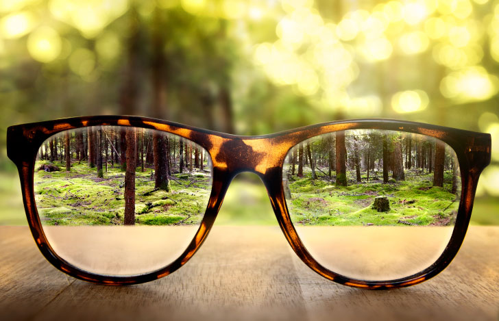 テーブルの上に置かれたメガネのレンズ越しに見る自然の風景