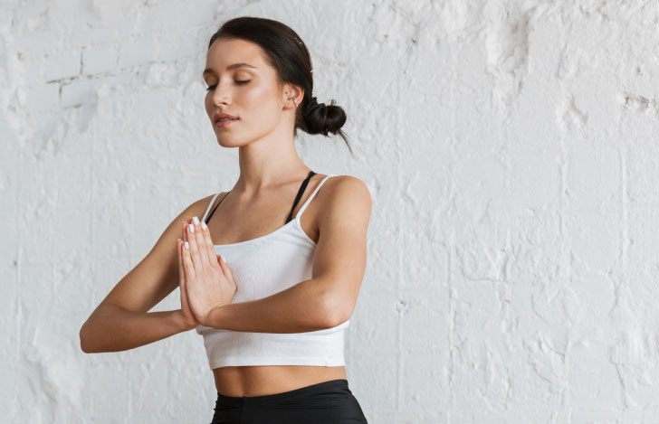 胸の前で合掌をして目を閉じる女性
