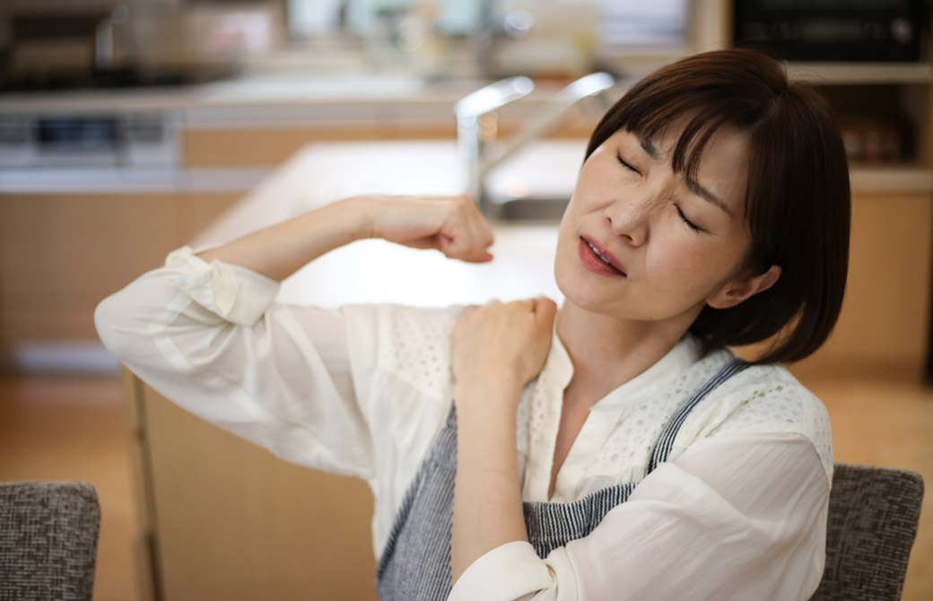女性が腕を上げたときに痛がっている様子