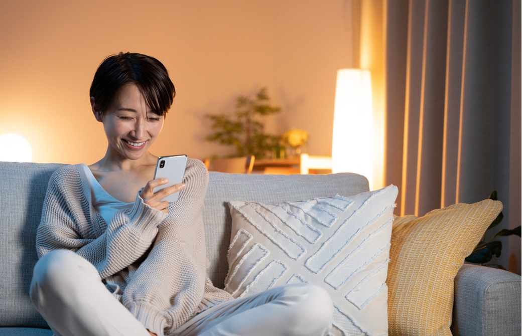 ソファーで携帯を見る女性