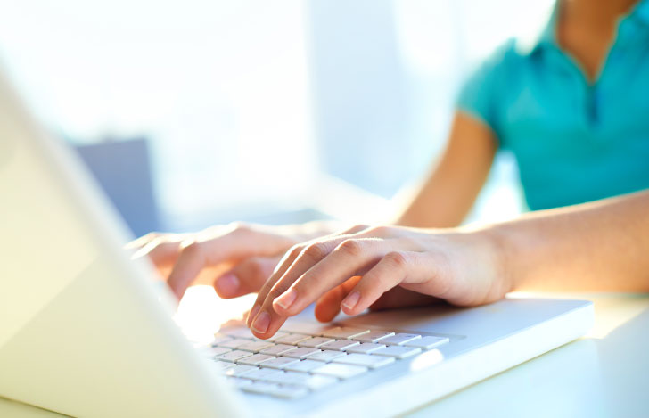 パソコンのキーボードを打つ少女の手元
