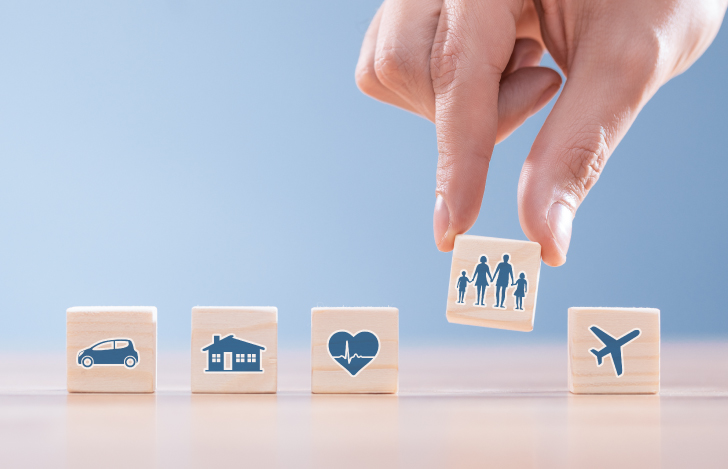 ライフイベントのアイコンが描かれた木の立方体をつまみ上げる人の手