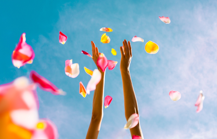 空に向かって花びらを投げる人の手