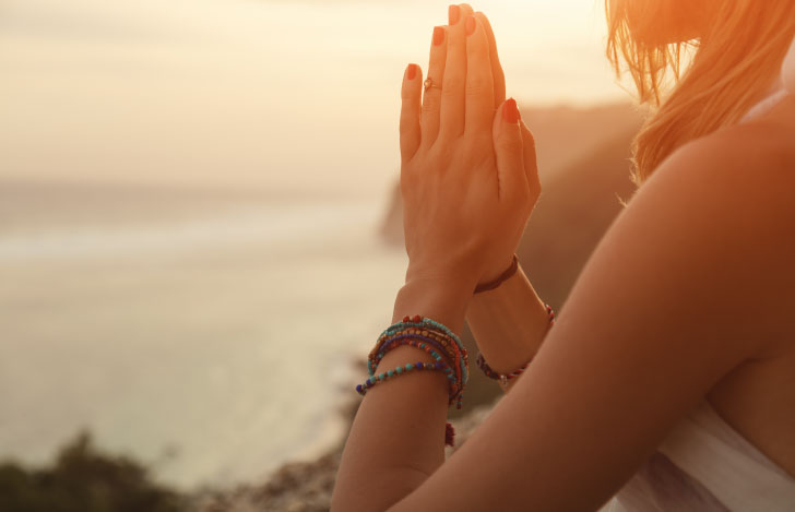 海に向かって胸の前で合掌をする女性