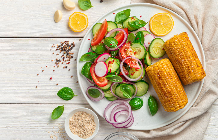 皿に盛り付けられたトウモロコシとキュウリとトマトなどのサラダ