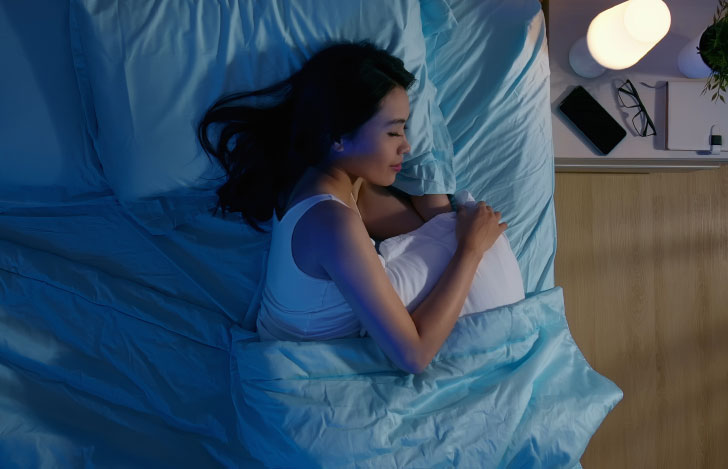 薄暗い部屋でタンクトップを着て快適そうに眠る女性