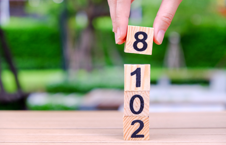 数字が描かれた木の積み木を摘み上げる人の手