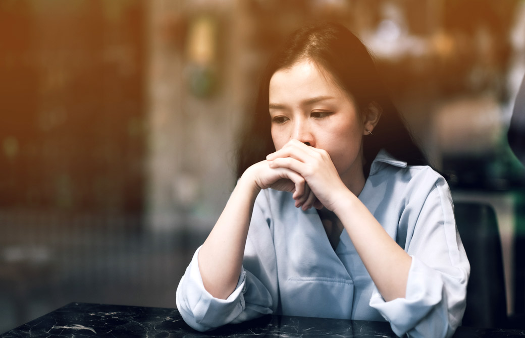 肘をついて、組んだ手に顔を乗せる女性