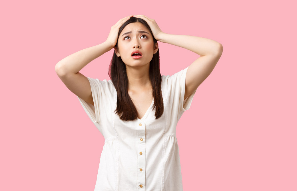 ピンクの背景に頭を抱える女性