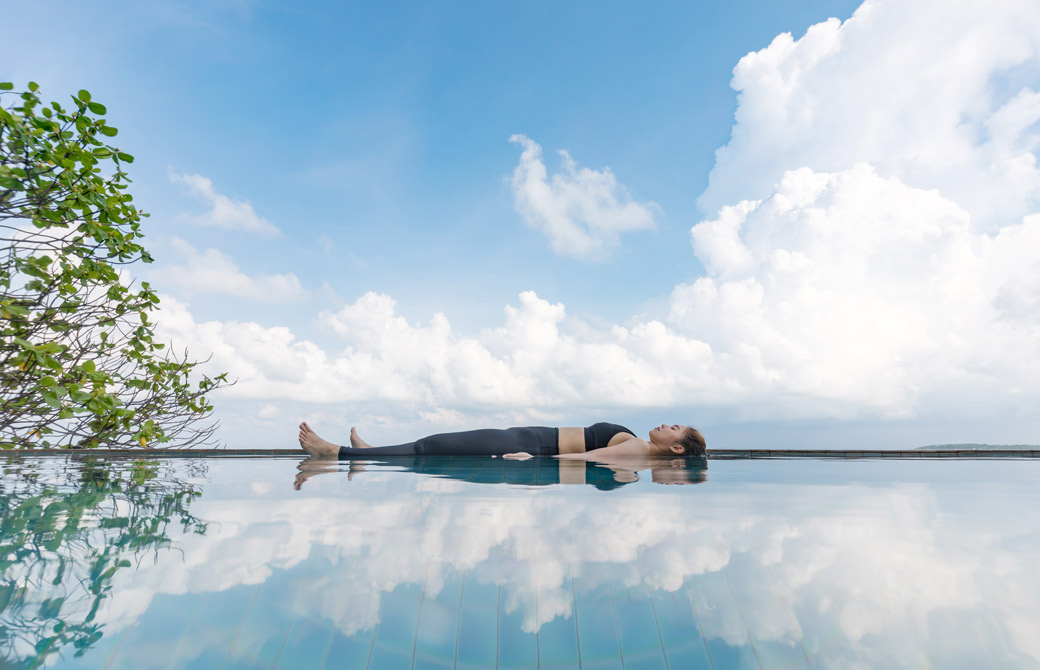 青空の下、水の上でヨガニードラをする人