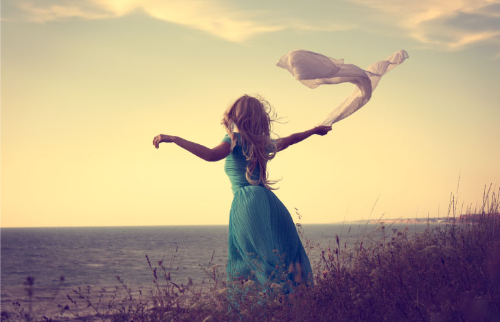 手に持った布をはためかせながら草原に向かって両手を広げる一人の女性