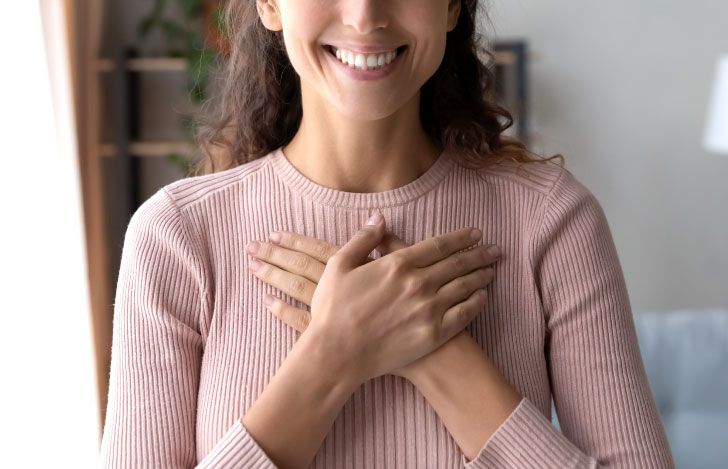笑顔で両手を胸に当てる女性