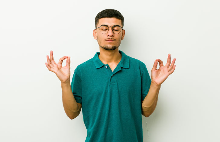 両手でチンムドラを組んで目を閉じるインド人の男性