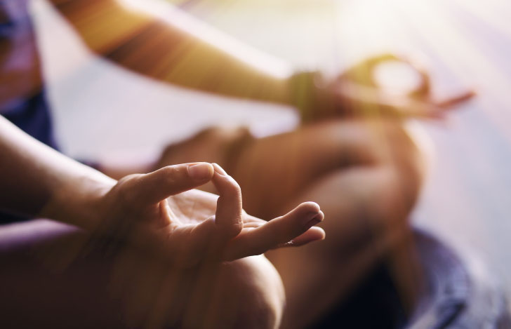 両手でチンムドラを組んで膝に載せている人の手元