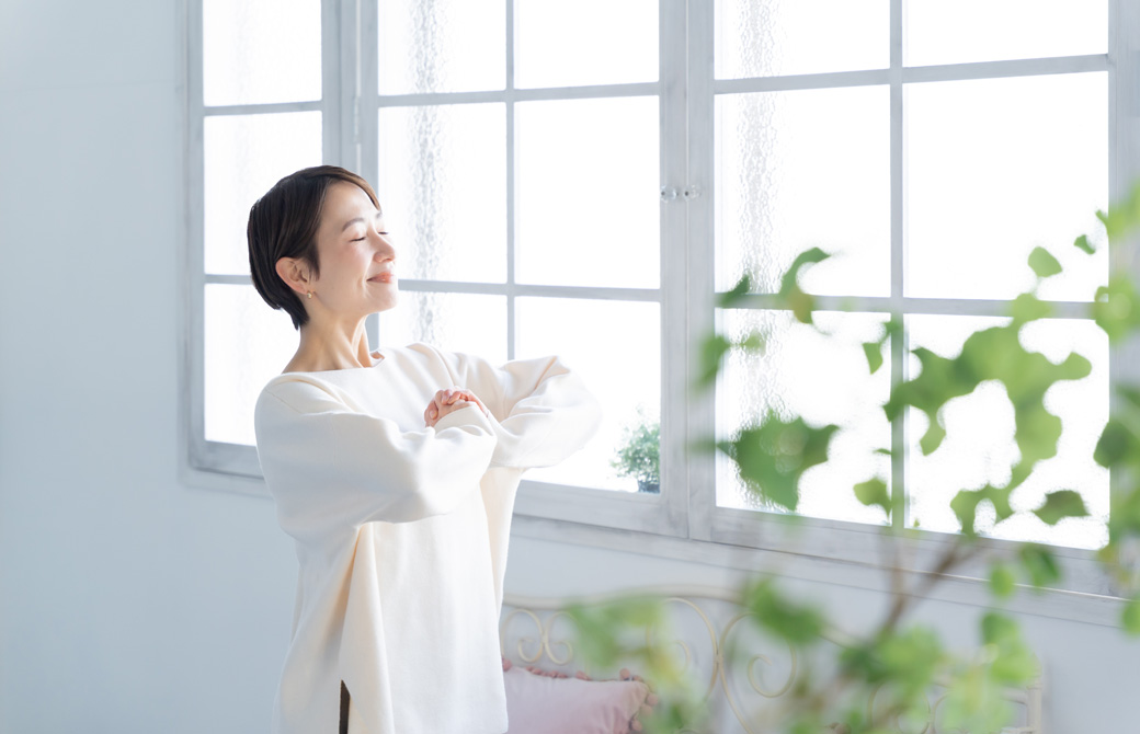 窓辺で手を合わせて目をつむる女性