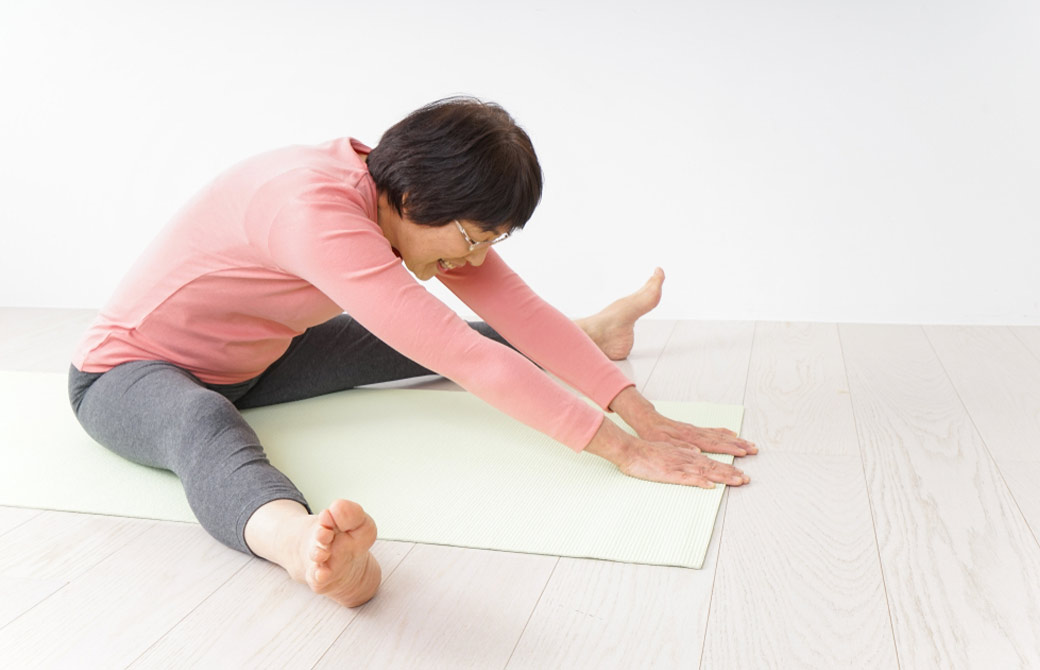 開脚前屈をするシニア女性