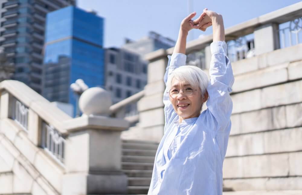 屋外で両手を上げる中井先生